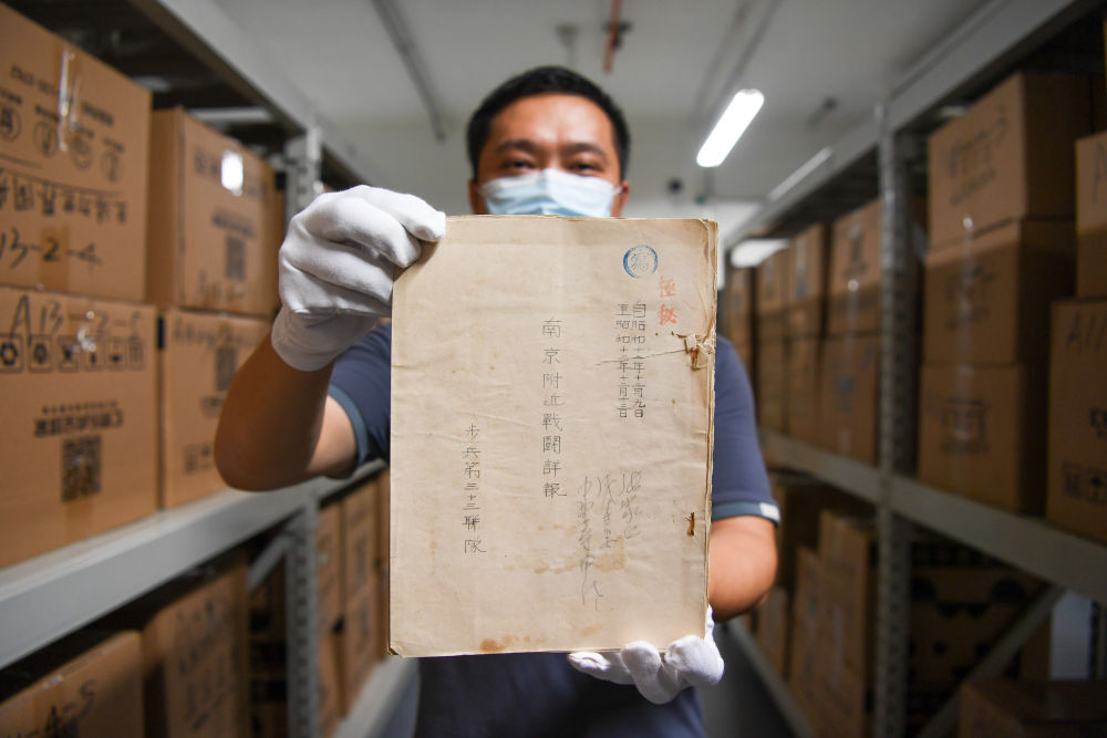 侵华日军南京大屠杀遇难同胞纪念馆工作人员展示封面标注为“极密”的步兵第三十三联队的《南京附近战斗详报》。新华社记者李博 摄.jpg