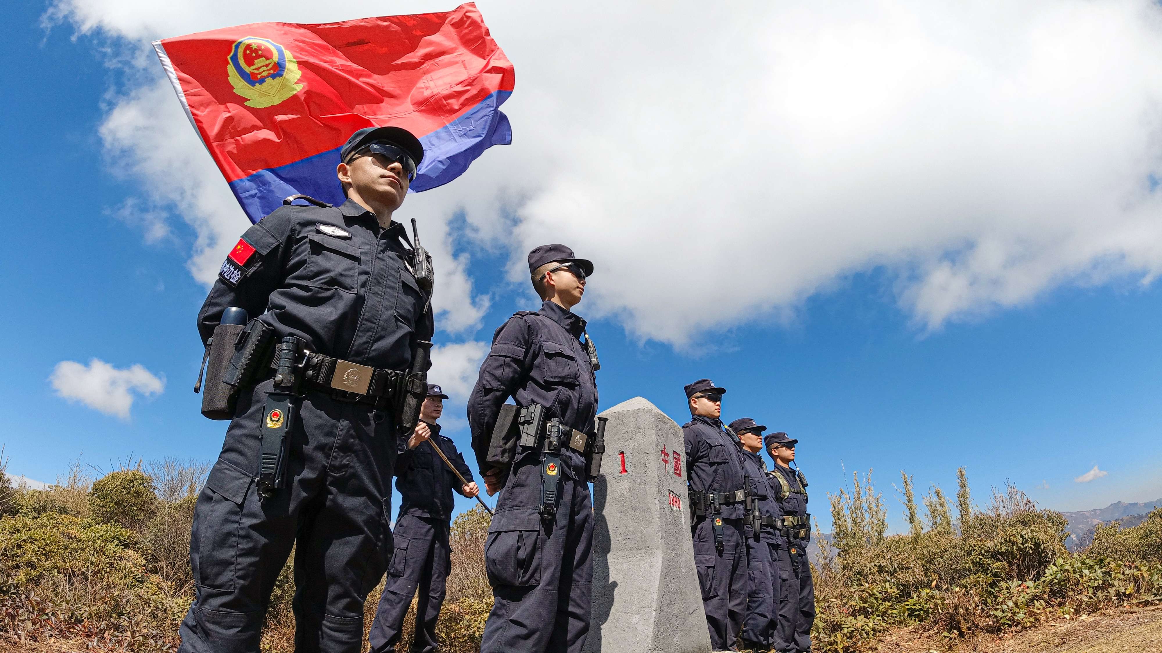 共和国一号界碑旁，腾冲出入境边防检查站民警与警旗同框  徐健勋摄影.jpg